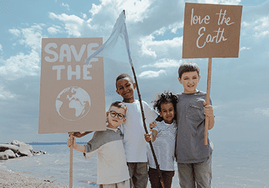Kids holding 'Save the planet' placards on a beach.