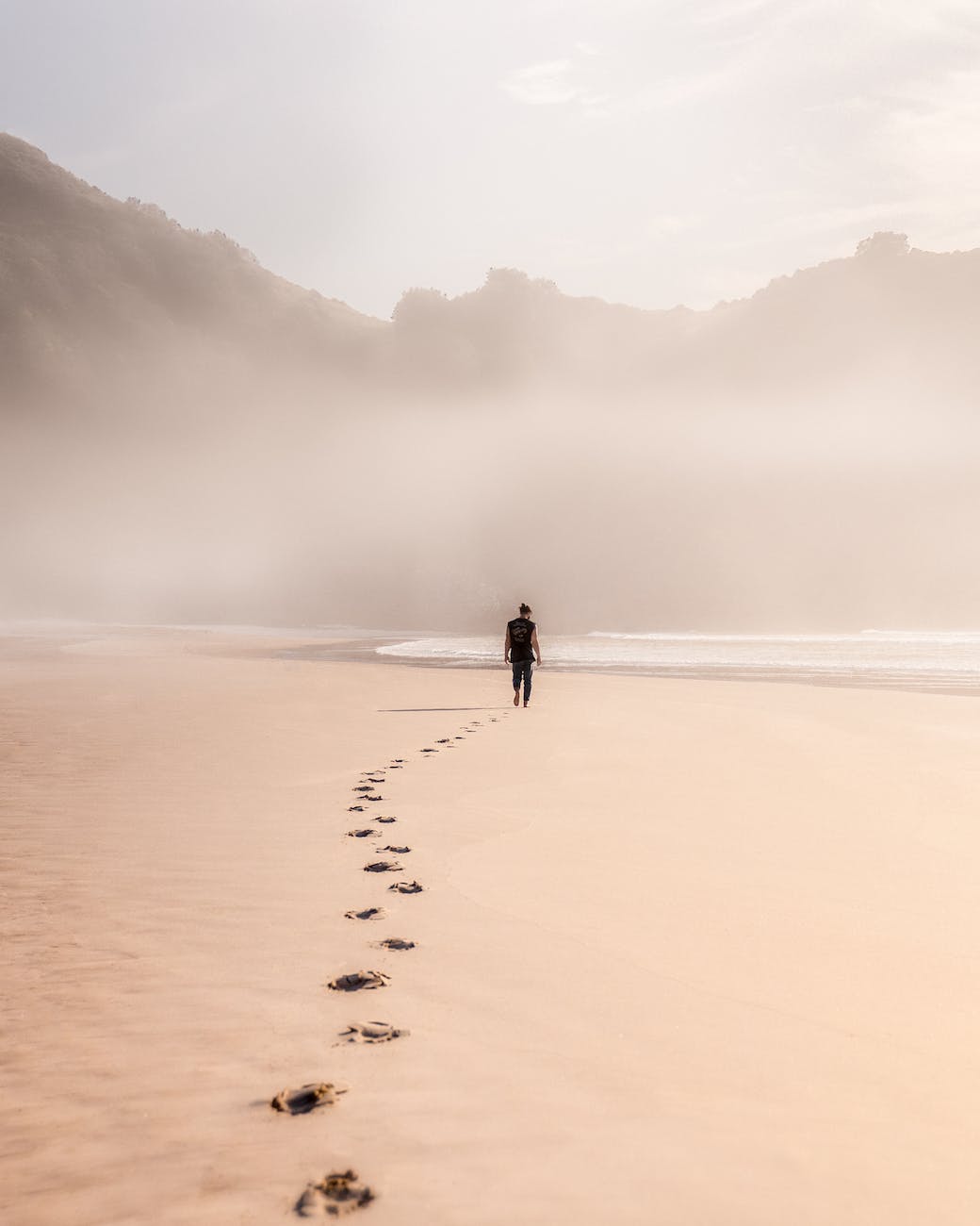 anonymous man walking on sandy seashore in misty weather carbon footprint