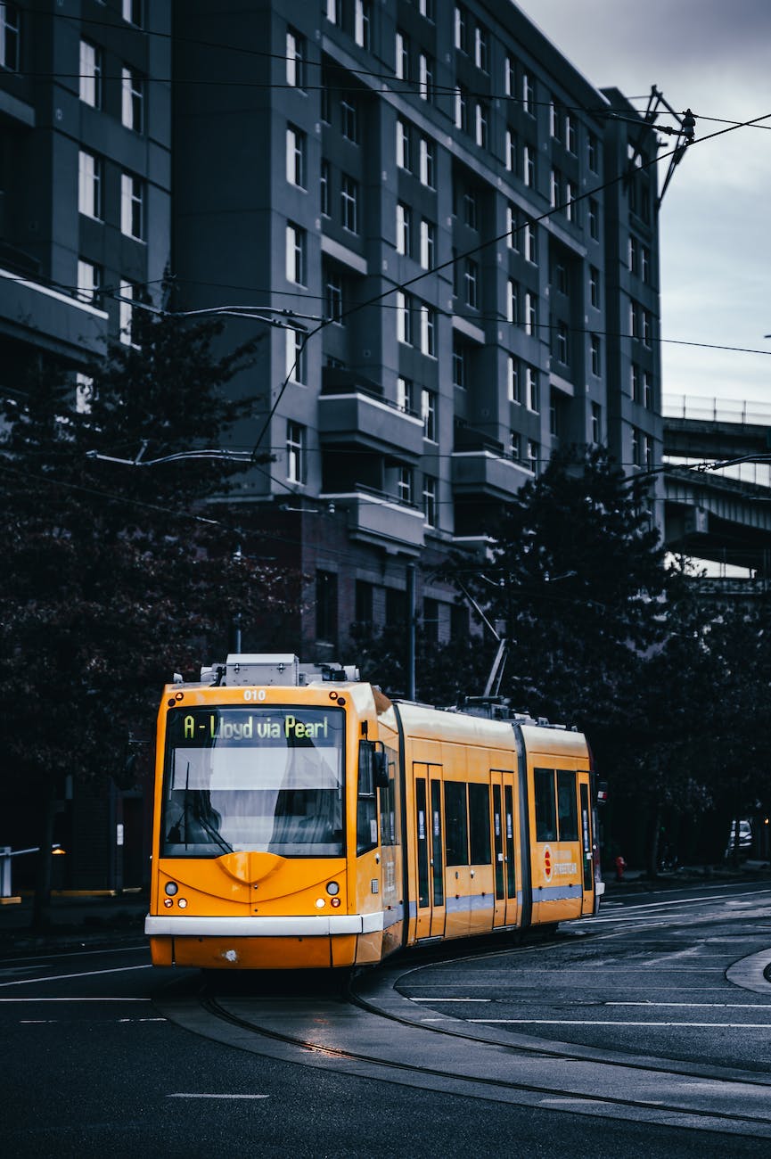 modern yellow tram riding along street